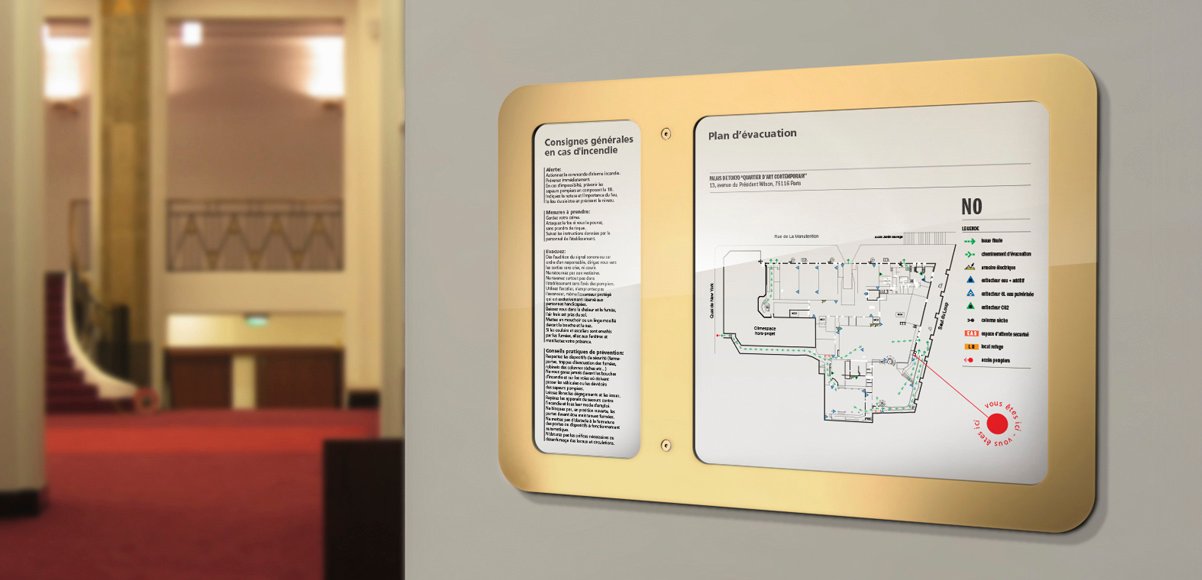 Plan d'évacuation encadré doré dans un hall corporate